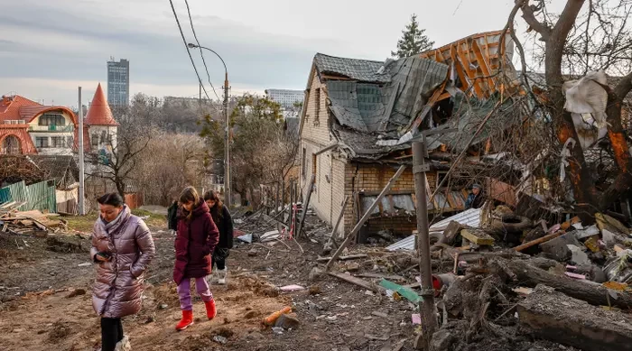 People walk through a damaged neighbourhood after the Russian missile attacks in the Solomyansk district of Kyiv, Ukraine, today.